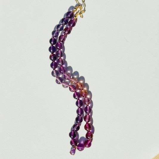 Beaded necklace with purple and pink beads on a light gray background